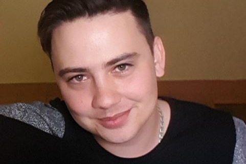 A portrait shot of a young man with dark hair, smiling.