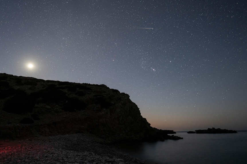 A meteor with a long white tail in the night sky