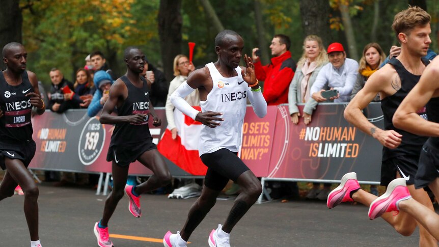 A male marathon runner amid a pack of other runners on a street in Vienna.