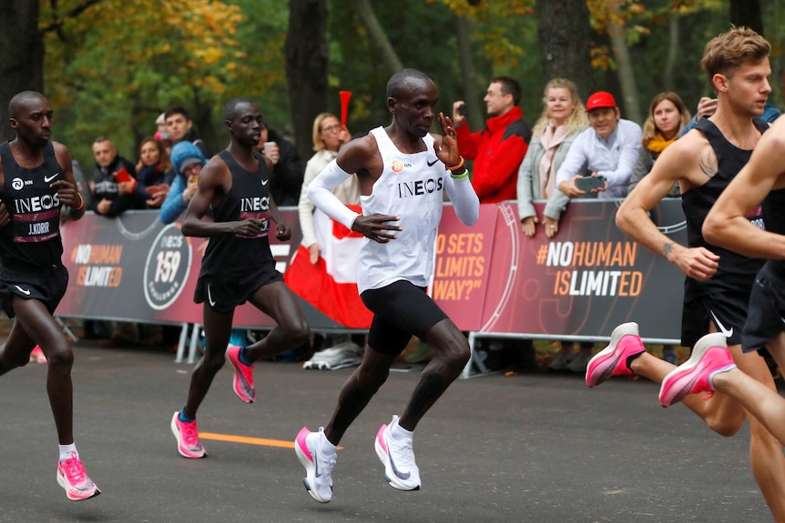 A male marathon runner amid a pack of other runners on a street in Vienna.