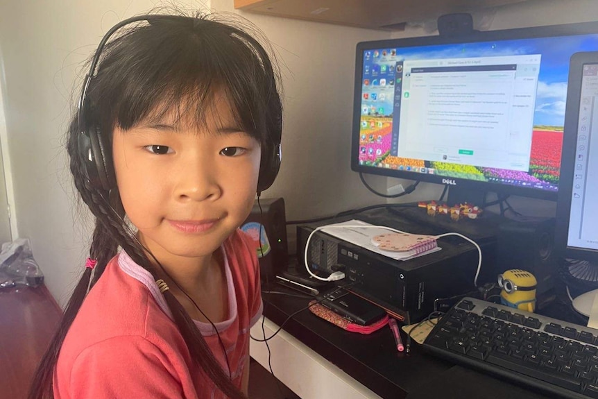Aileen在书桌前学习带着耳机。