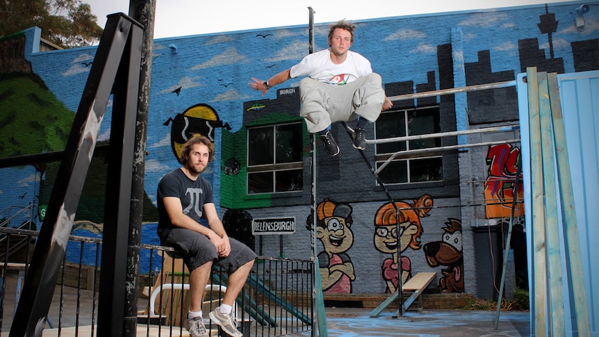 Matt Sanderson sits on a fence while Anthony Smith is airborne at a Parkour circuit in Helensburgh.