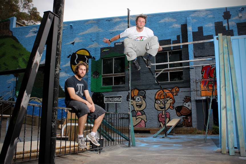 Matt Sanderson sits on a fence while Anthony Smith is airborne at a Parkour circuit in Helensburgh.
