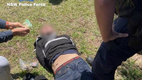 Man being arrested lying on the ground surrounded by police