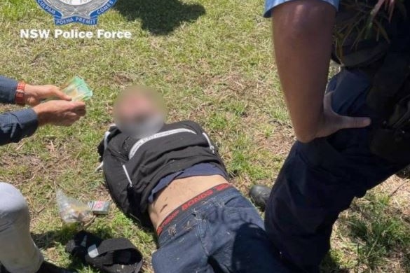 Man being arrested lying on the ground surrounded by police