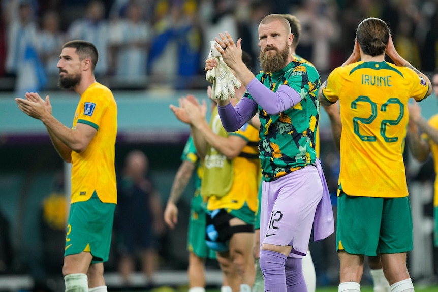A group of Socceroos applaud the fans and thank them after the end of their final World Cup game.