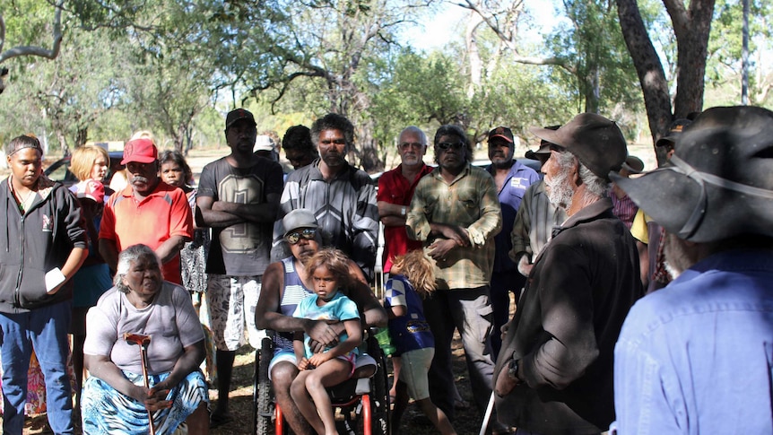 a group of indigenous people standing in the shade
