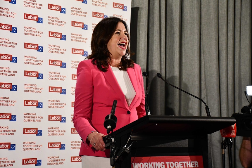 A woman in a pink jacket smiles.