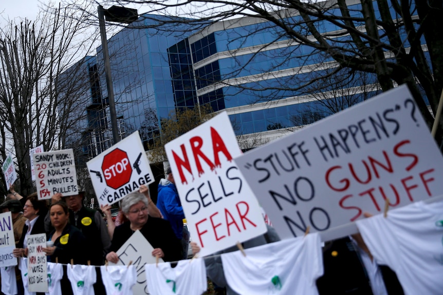 Activists hold placards protesting gun violence outside NRA HQ on the third anniversary of the Sandy Hook shooting.