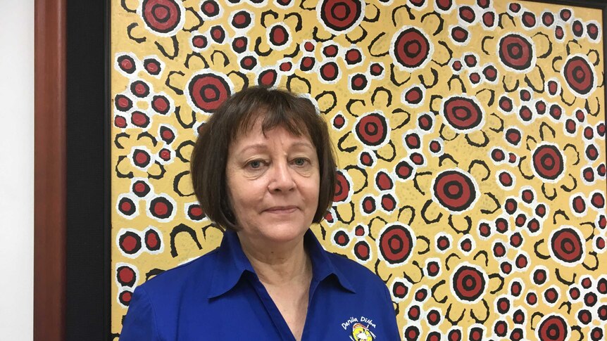 Indigenous leader Olga Havnen stands in front of a painting in her office.
