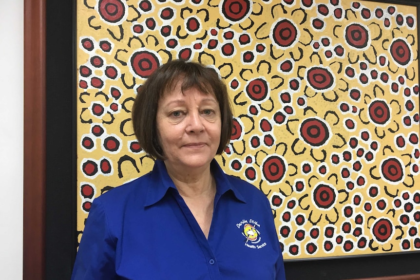 Indigenous leader Olga Havnen stands in front of a painting in her office.