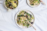 A bowl of pad thai salad with tongs served onto two dinner plates with chopsticks, illustrating our simple recipe.