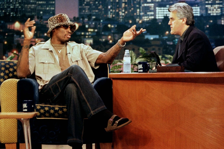 Basketballer Dennis Rodman wears a a leopard print hat while being interviewed by Jay Leno