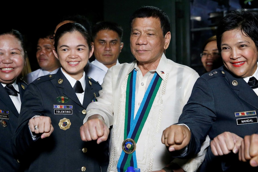 Duterte looks smug as he fist bumps with four female military officers