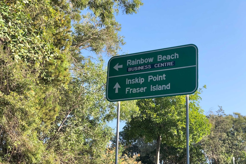 A sign among trees pointing the way to Rainbow Beach.