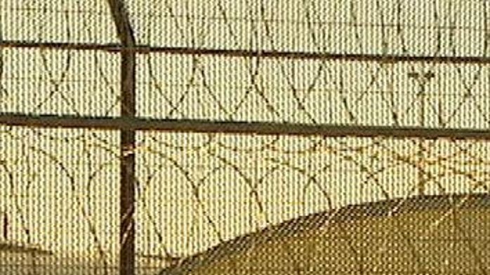 Good generic shot of prison buildings with barbed wire fencing in the foreground