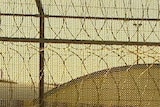 Good generic shot of prison buildings with barbed wire fencing in the foreground