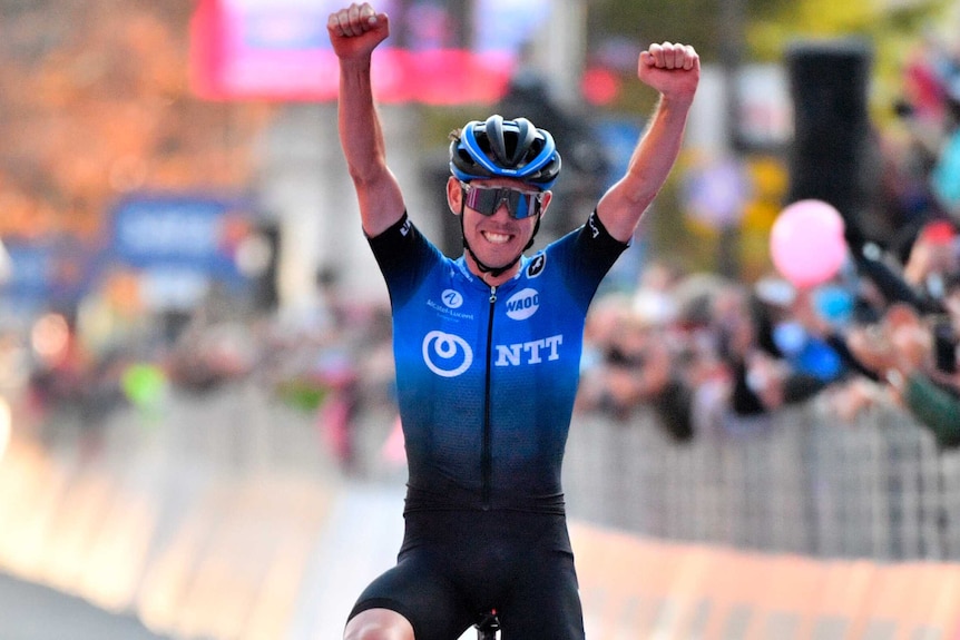 Ben O'Connor raises his arms above his head as he crosses the finish line at the Giro d'Italia.