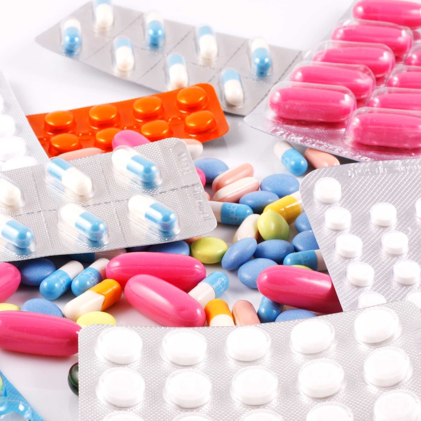 A pile of blister packs containing colourful tablets on a white background