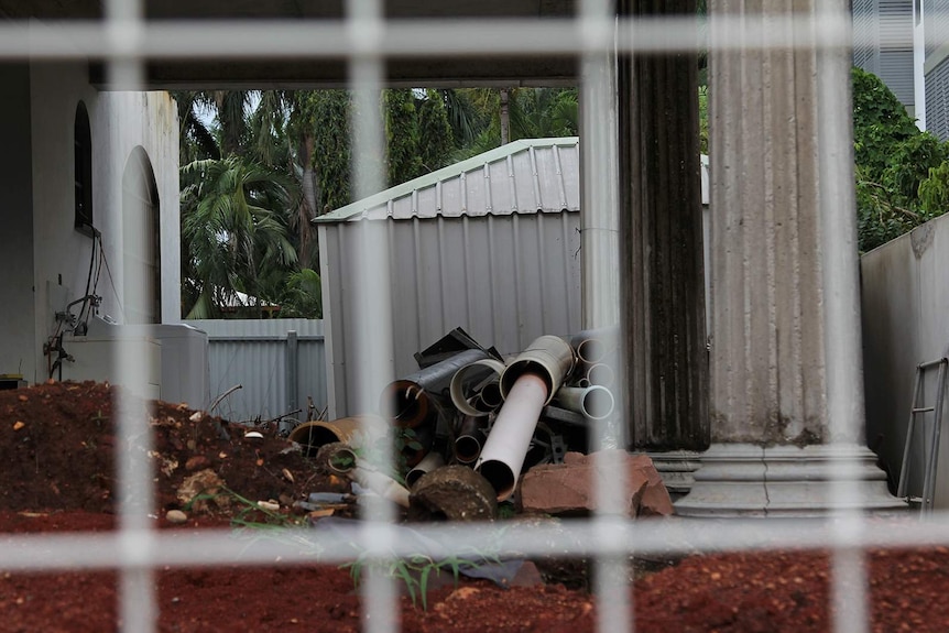 PVC pipes as seen through the fence of an unfinished house.