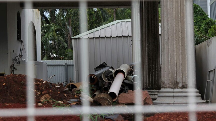 PVC pipes as seen through the fence of an unfinished house.