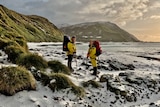 Female expeditioners on a snow covered beach on a remote island.