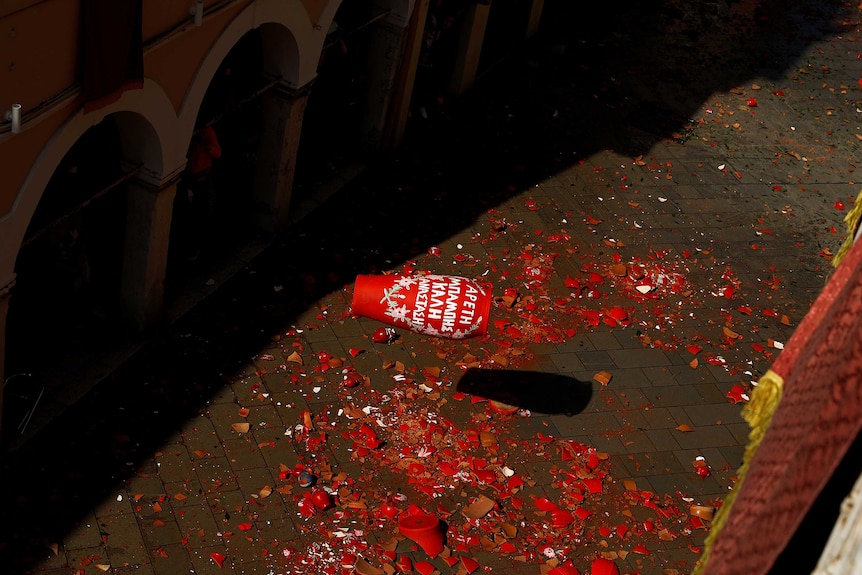 A clay pot filled with water is seen before hitting the ground.