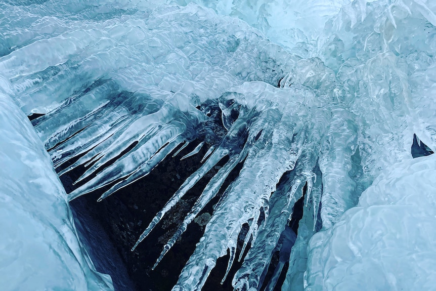 IJzige pieken van bevroren water hangen aan een rotsachtige overhang.