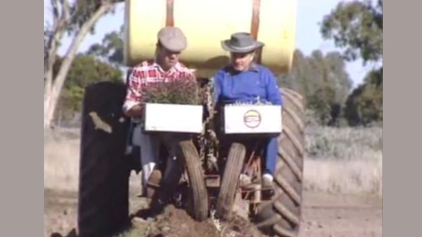 Two men sit in front of tractor