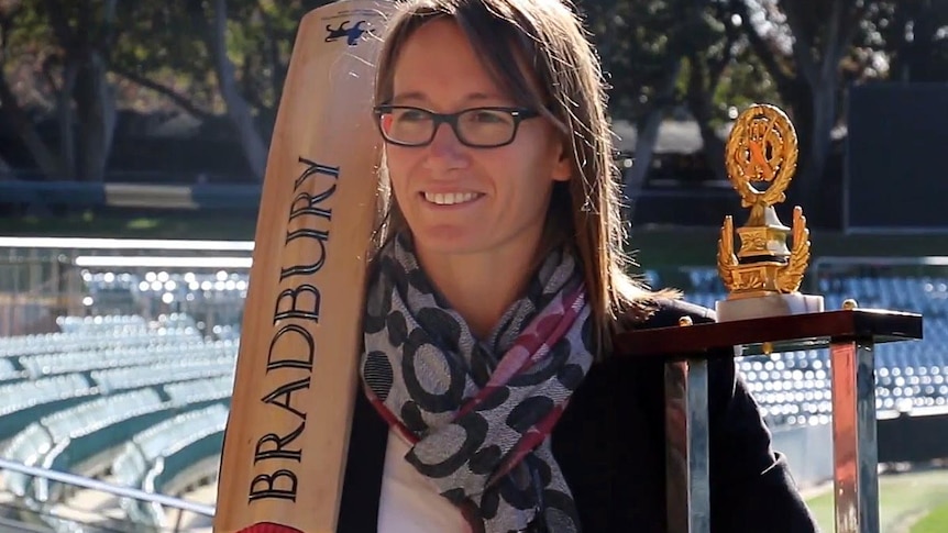 Lauren Ebsary holds a cricket bat and trophy.