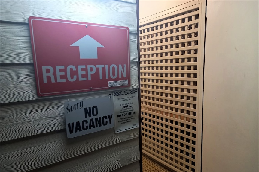 A red reception sign hanging on a wall next to a "no vacancy" sign.