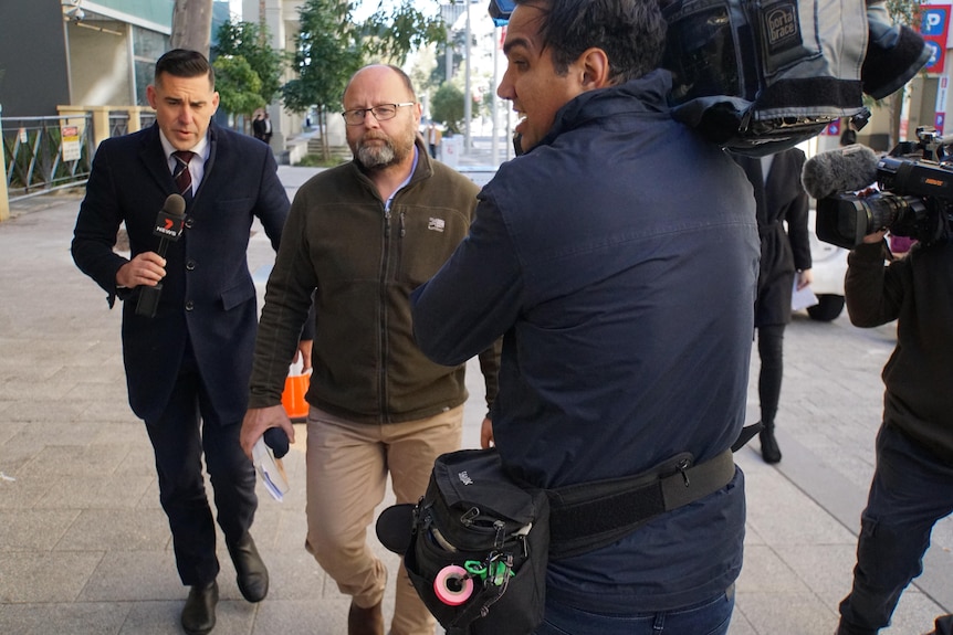 A photograph of Barry Urban walking outside court next to a journalist.