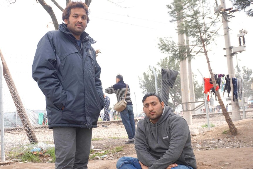 Sayed Ahmed and a friend pose for a photo in front of the border fence.