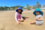 Two toddler girls playing in the sand.