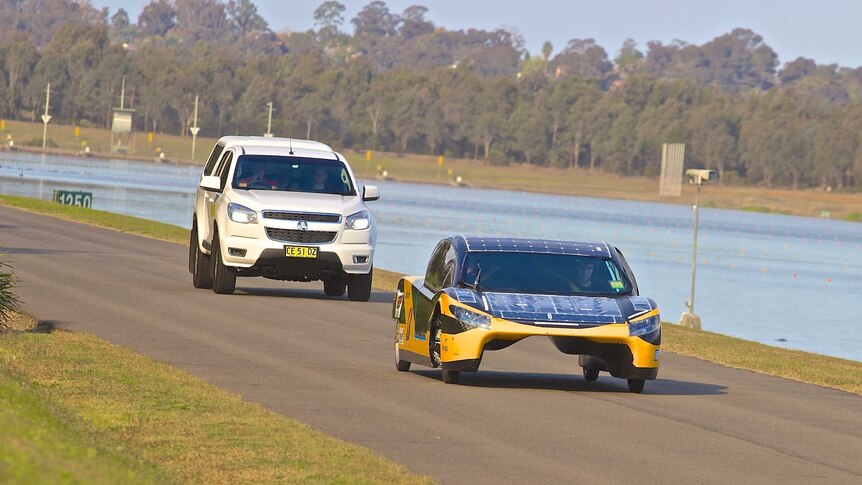 The solar car almost looks like a land catamaram - it's wheel base is wide with a gap in between. Solar tiles clearly seen.