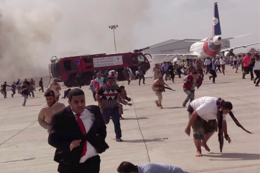 People run from an explosion across an airport tarmac.