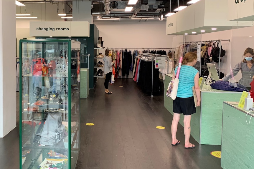 a clothing store with racks of clothes and shoppers