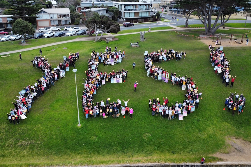 A crowd of Voice supporters form a human 'YES' near Cosy Corner Beach in Torquay