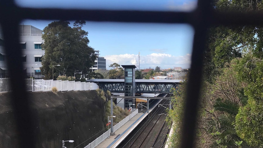 Wollongong Railway Station through mesh fence on a blue sky day.
