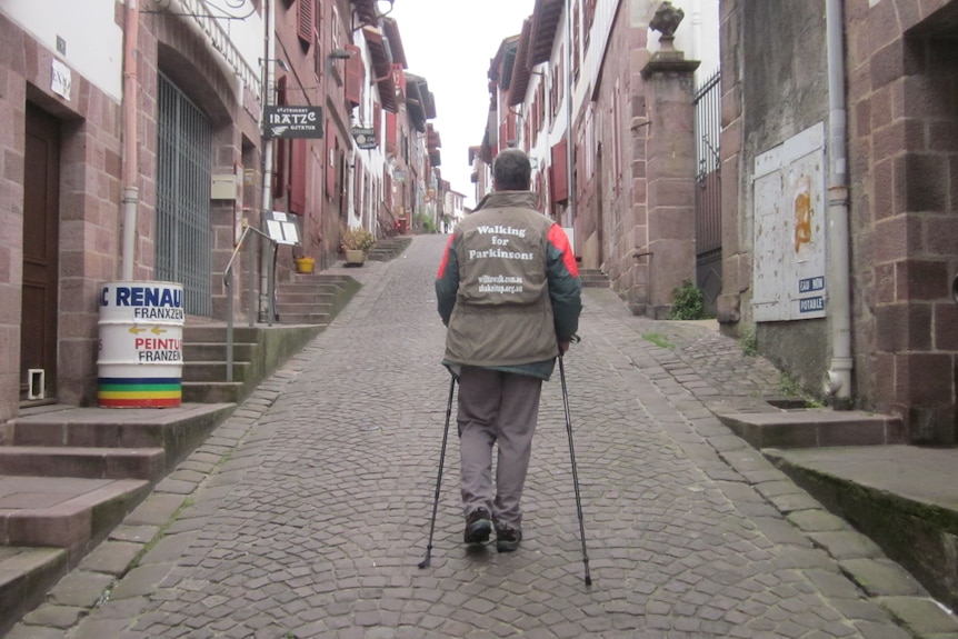A man walks through a cobblestone lane in a village. 