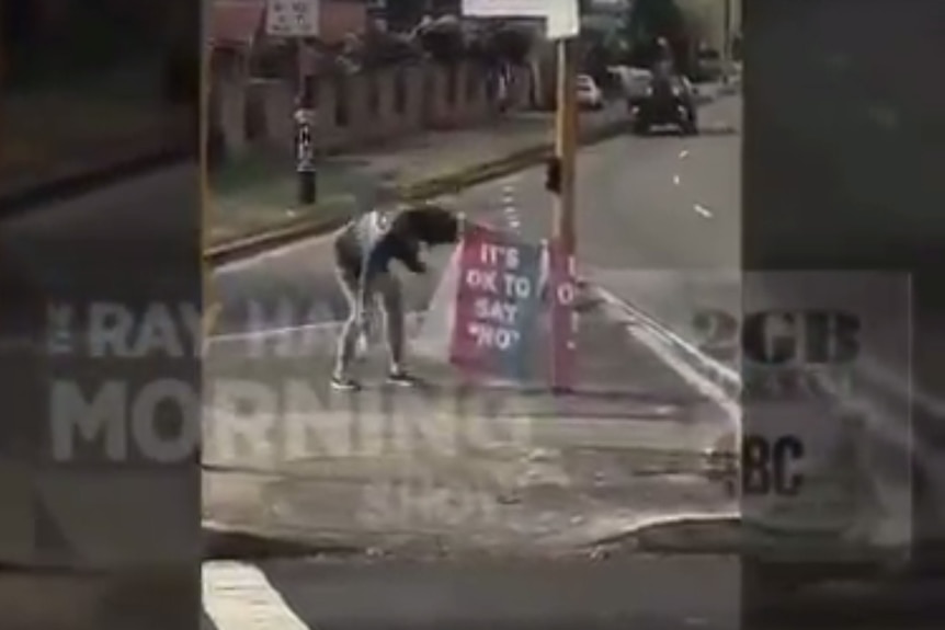 A woman takes down Vote No signs at an intersection.