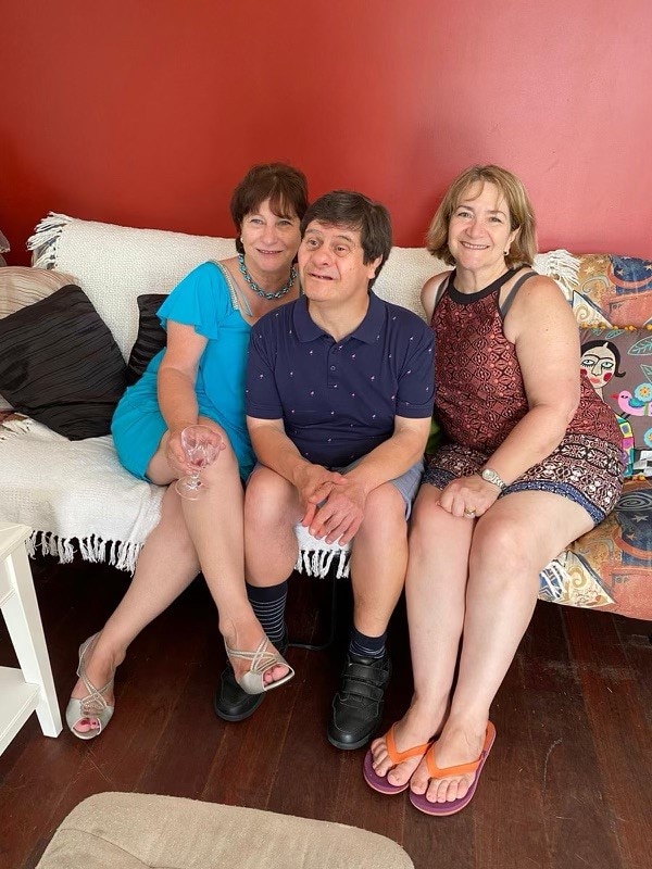 Carrmen, Louie and Gabrielle sitting on a comfortable looking couch and smiling.