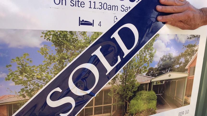 Auction sign on house covered with sold sticker