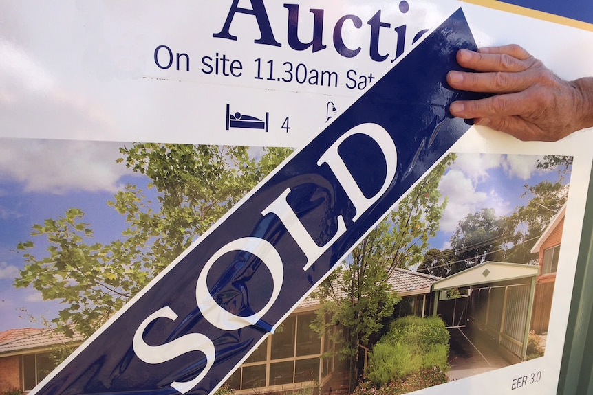 Auction sign on house replaced with sold sign
