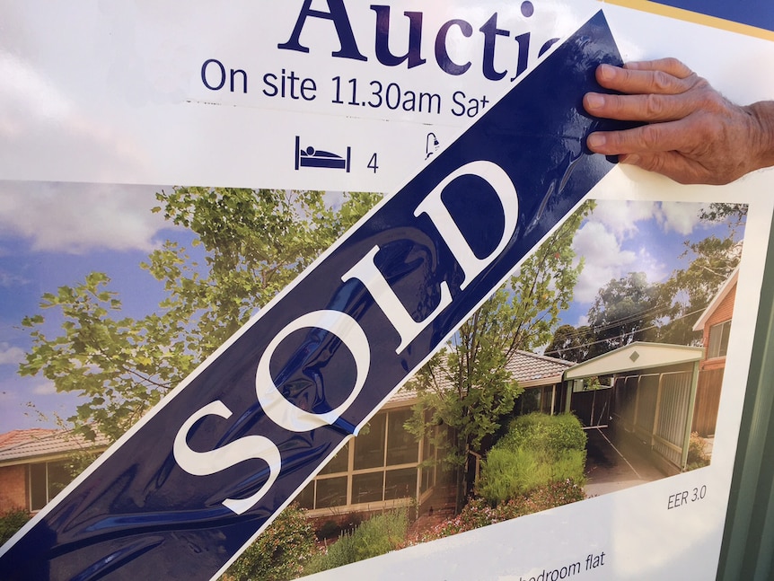 A sold sticker is put over the top of an auction sign
