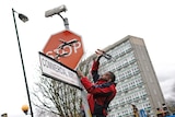 A man climbing up a post to pull out a stop sign