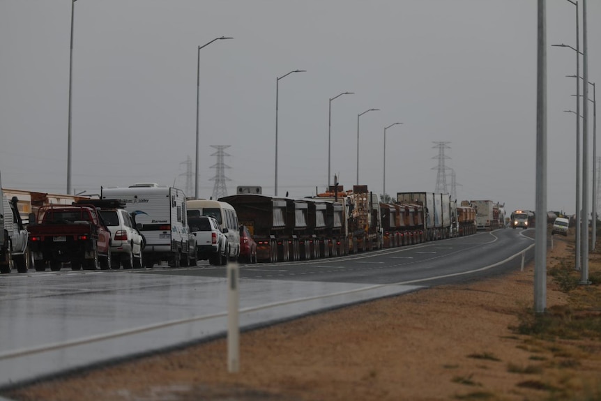 A line of cars, buses, road trains on the left hand side of the road