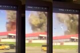 A blury picture of a screen showing smoke rising from a building