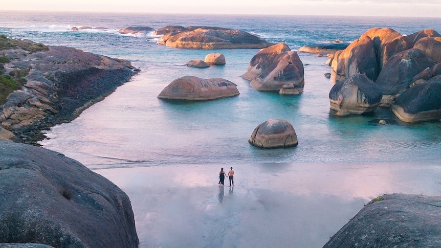 A sunrise of some large rocks poking out of the ocean.