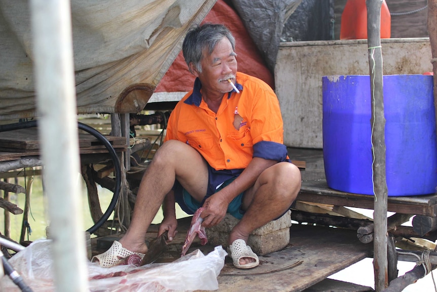 a man sitting cutting up meat